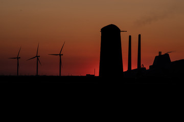 Green energy and fossil fuel wind turbines and powerplant silhouette against the red sunset sky Amager, Copenhagen, Denmark, Amager F&aelig;lled