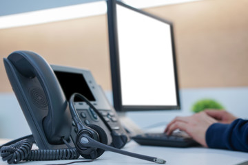 close up on headphone telephone with employee working at desktop table in office room concept