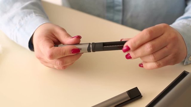 Close-up of the girl changes the insulin cartridge in the insulin syringe pen before use. A diabetic patient makes a self-injection of insulin at home with a modern syringe pen.