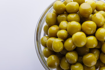 canned green peas in a glass bowl on a white background