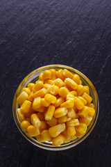 canned corn in a glass bowl on a dark stone background