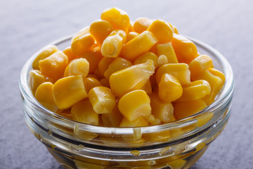 canned corn in a glass bowl on a dark stone background