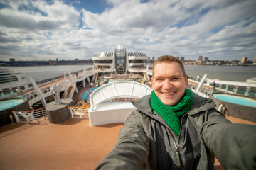 Young man makes selfie with huge cruise ship and city on background