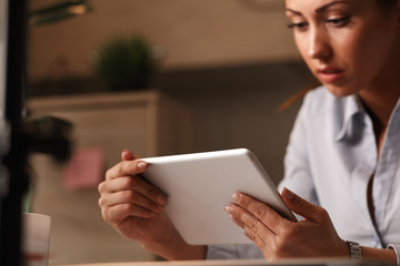 Close up of female entrepreneur reading reports on digital tablet.