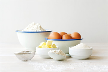 Ingredients for making dough, dessert on white wooden table. Flour, butter, sugar, eggs ingredients
