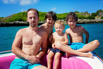 Fototapeta na wymiar Happy beautiful family, children and parents, dressed in beach wear, enjoying day trip with speed boat