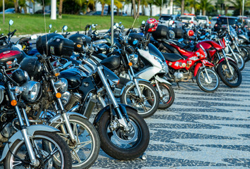 Front wheels of motorcycles exposed in a parking lot. Several parked motorcycles. 
