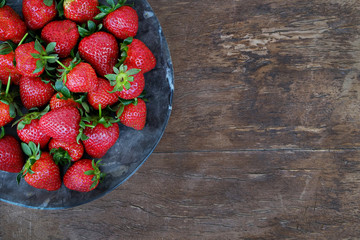 Ripe local produce organic strawberry. Heap of red berries on plate. Fresh healthy vegan dietary food for spring detox. Fruits background, top view. Clean eating concept.