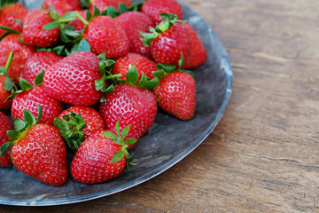 Ripe local produce organic strawberry. Heap of red berries on plate. Fresh healthy vegan dietary food for spring detox. Fruits background, top view. Clean eating concept.