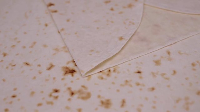 Close up macro shot of layers of pita bread roating slowly on table right to left. Gimbal shot top view of unfolded shawarma pita layer dough slowly rotating