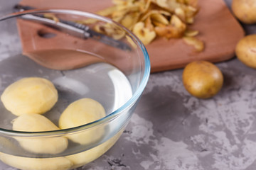 A young woman in an apron peeling potatoes