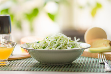 Bowl of vegan healthy raw vegetable salad - daikon radish, celery, cucumber and spring onions - organic cuisine. Close-up.