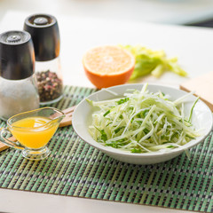 Dietary vegetarian salad made from daikon radish, celery, cucumber and spring onions in a plate and with ingredients on the table - an organic dish. Japanese cuisine.