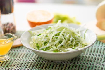 Bowl of vegan healthy raw vegetable salad - daikon radish, celery, cucumber and spring onions - organic cuisine. Close-up.