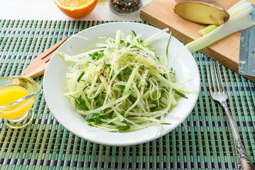 Bowl of vegan healthy raw vegetable salad - daikon radish, celery, cucumber and spring onions - organic cuisine. Close-up.