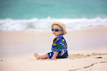 Cute toddler baby boy playing with beach toys on tropical beach