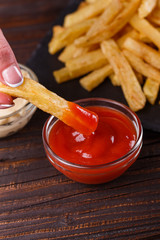 young woman dip french fries to tomato sauce