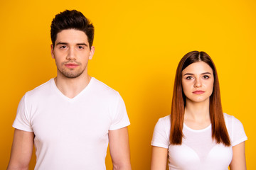 Close up photo two cool amazing beautiful she her he him his couple standing side by side not smiling look through like zombie wearing casual white t-shirts outfit clothes isolated yellow background