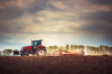 Photo sur Plexiglas Tracteur Agriculteur en tracteur préparant la terre avec cultivateur de lit de semence