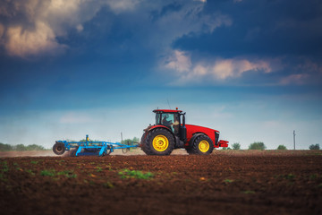 Farmer in tractor preparing land with seedbed cultivator