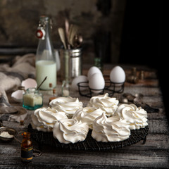 Fototapeta na wymiar Homemade white mini meringue desserts pavlova on Wicker metal stand on grey wooden table 