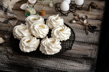 Homemade white mini meringue desserts pavlova on Wicker metal stand on grey wooden table 