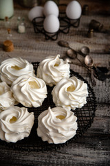 Obraz na płótnie Canvas Homemade white mini meringue desserts pavlova on Wicker metal stand on grey wooden table 