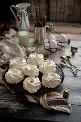 Homemade white mini meringue desserts pavlova on Wicker metal stand on grey wooden table 