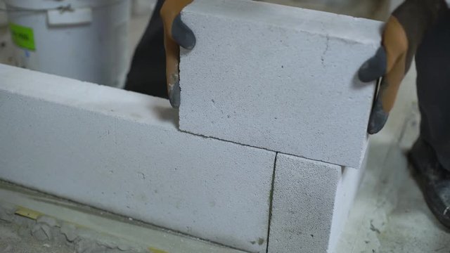 view of builder hands scrubbing block to customize it to lower layer