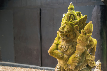Obraz premium Balinese Carved Stone Statue of Rakasa covered with green moss.Thailand.