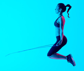 one mixed races woman exercsing jumping rope fitness exercices isolated on blue blackground