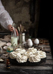 Homemade white mini meringue desserts pavlova on Wicker metal stand on grey wooden table 