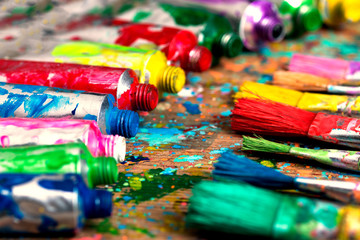 Fototapeta premium Stained paint brushes and acrylic pain tubes on artist table. Artistic background
