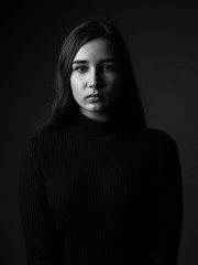 Portrait of the young woman on black background. Black and white.