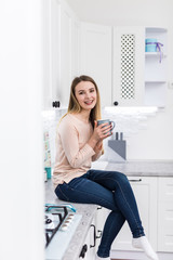 Young happy woman drinking coffee on the kitchen in the morning.