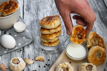 Homemade pies with meat, stick with sour cream on a gray background. © Оксана Клименко