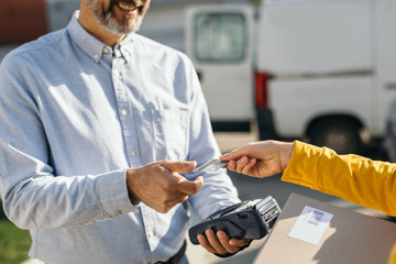 woman paying to a courier with a credit card for package delivery