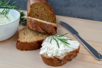 Sliced bread with light cheese on a wooden board.