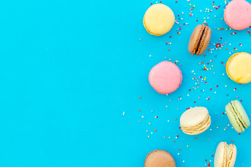 Brignt macarons for sweet break on blue background top view mock up