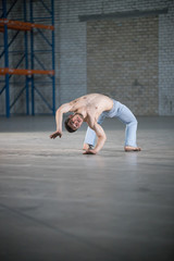 Fototapeta premium An athletic man on capoeira training. Standing on the bending over backwards position