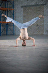 An athletic man on capoeira training. Standing on the hands with legs apart