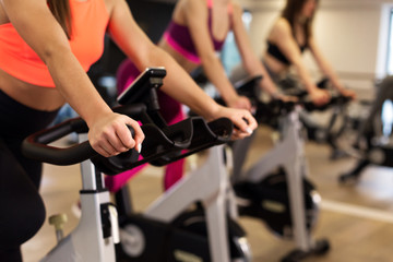 Fototapeta na wymiar Group of young slim women workout on exercise bike in gym. Sport and wellness lifestyle concept