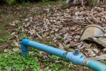 Old water valve with blue plastic pipe in garden