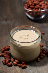 peanut butter in a glass jar on a wooden background, vertical