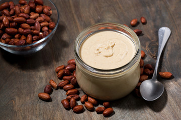 peanut butter in a glass jar on a wooden background, top view
