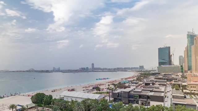 Aerial view of beach skyline and tourists walking in JBR timelapse in Dubai, UAE. Skyscrapers on a background. Waterfront with many activities and attractions, shops and restaurants