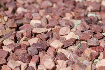 Making flower beds multicolored rubble. Crushed stone of red color on a flower bed. Selective focus. Design flower beds with stone.