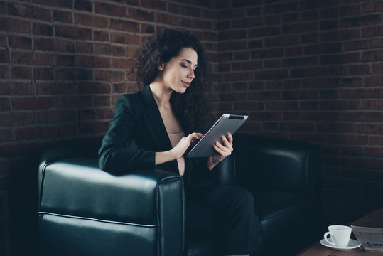 Portrait of beautiful stylish agent executive search news read see notifications modern technology use user sit divan loft long wavy curly hair wear black jackets have mug beverage table industrial 