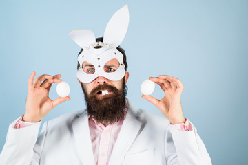 Easter man. Rabbit man. Bunny man. Easter egg. Tradition of Easter. Happy Easter day. Coloring eggs. Rabbit mask. Eggs hunt. Handsome man holds white eggs. Religion symbol. Spring holidays. Bunny ears