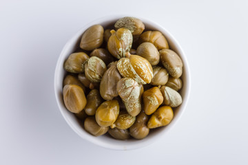 Pickled capers on a white acrylic background